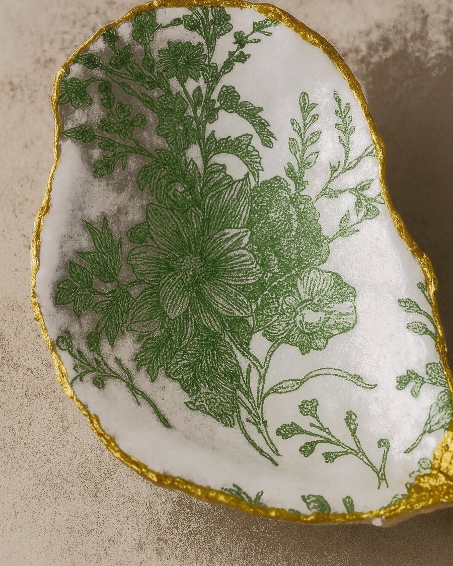 A single green botanical oyster dish with a gold leaf rim
